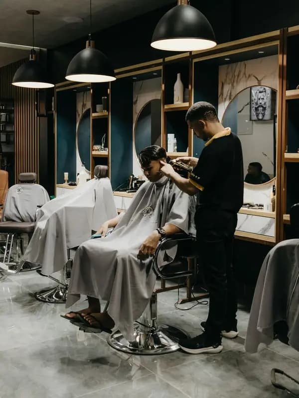 A barber cuts a client's hair with clippers